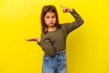 Little caucasian girl isolated on yellow background holding and showing a product on hand.