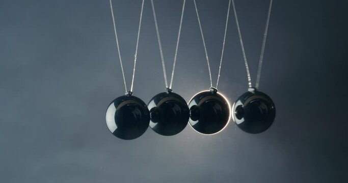 Balls in Newton's pendulum hit each other in the light of the spotlight beam