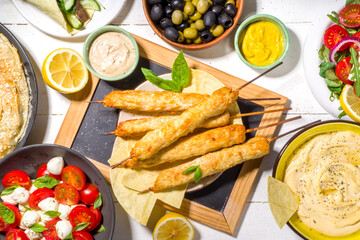 Chicken shish kebabs on wooden skewers sticks top view. Traditional Mediterranean dish kebaps with ground chicken meat, sunny white wooden background copy space