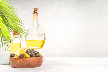 Mediterranean traditional food. Green and black olives with bottles of olive oil on white wood...