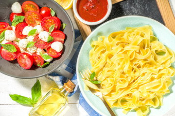Mediterranean traditional food. Simple Italian pasta Fettuccine with basil and sauces, on a white wooden table