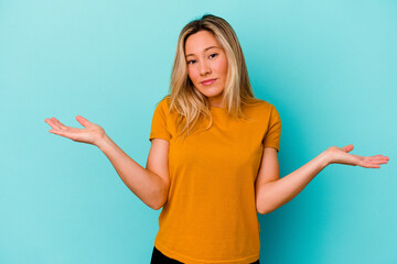 Young mixed race woman isolated on blue background doubting and shrugging shoulders in questioning gesture.