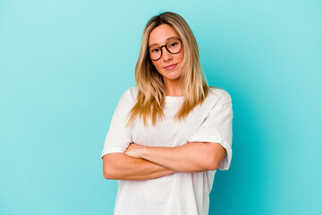 Young mixed race woman isolated on blue background who feels confident, crossing arms with determination.