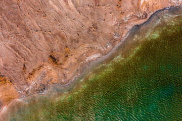 Aerial view about rocky seashore with turquoise waving water.