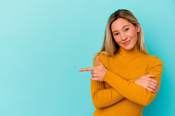 Young mixed race woman isolated on blue background smiling cheerfully pointing with forefinger away.