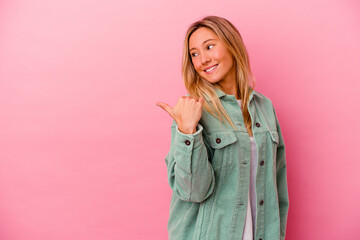 Young mixed race woman isolated on pink background points with thumb finger away, laughing and carefree.