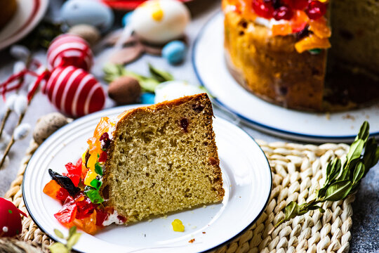 Slice of Easter cake with glace fruit on a table with Easter decorations