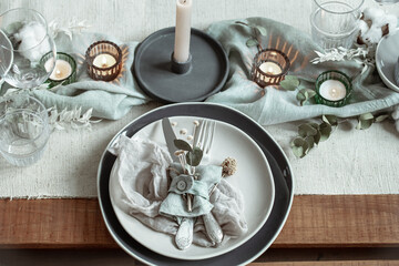 Festive table setting in vintage style with dry sprigs of leaves close up.