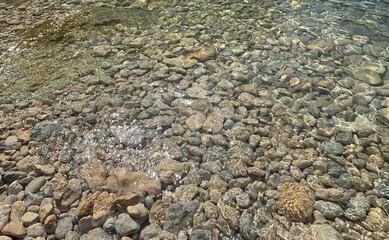 Sea transparent water, crystal clear sea water surface on pebbles beach. Zen landscape, mediation of nature, beautiful seascape, sunlight on stones.