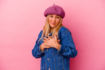 Young mixed race woman isolated on pink background has friendly expression, pressing palm to chest. Love concept.