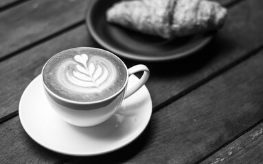 Coffee latte with croissant on a wooden table