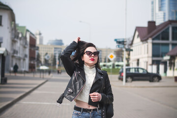 A beautiful hipster girl with a phone in her hands walks down the street