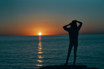 Fototapeta premium woman gesturing with her hands and sunset sea landscape beach