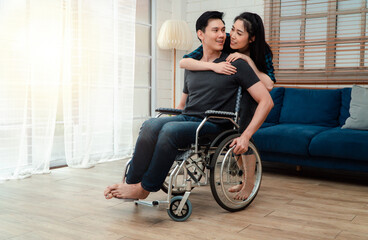 An asian man in a wheelchair in the home after a car accident and his wife to give encouragement....