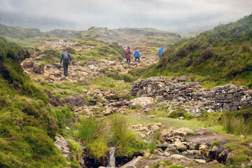 Tourists walking in a mountains, Croagh Patrick trail. Westport, county Mayo, Ireland. Mist over mountain peak.