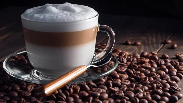 Cup with hot cappuccino drink on roasted coffee beans. dolly shot