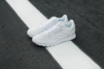 White women skeakers on a white line on road