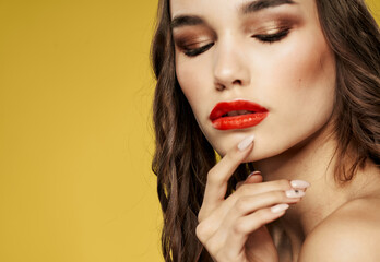 Portrait of a woman with bright makeup on a yellow background bared shoulders cropped view