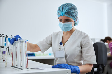 Biochemist analyzing the blood samples in the calibrated serological pipettes