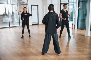 Woman coach watching over two martial arts learners