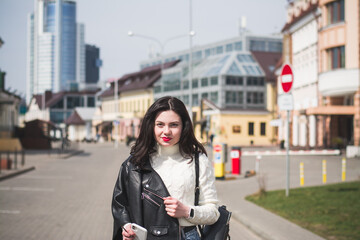 A beautiful hipster girl with a phone in her hands walks down the street