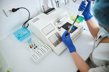 Lab worker conducting a coagulation test using an automated pipette © Svitlana