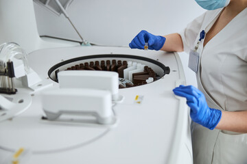 Biochemist holding a glass vial with liquid over the reagent tray