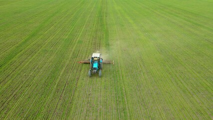 Drone sliding shot of farmer in tractor plowing crops after sowing barley and wheat at field. Concept of work in agricultural farm for making business and having profit from production food - Powered by Adobe