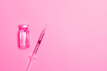 Syringe with medicine from glass vial on light pink background. Vaccination against influenza, covid 19, measles, coronavirus disease. Vaccination and immunization concept