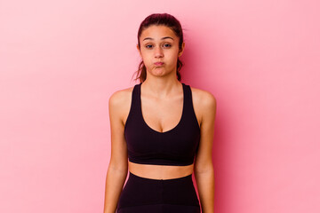 Young sport Indian woman isolated on pink background blows cheeks, has tired expression. Facial expression concept.