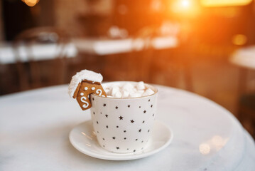 The mug with the christmas decorations and cookie on edge