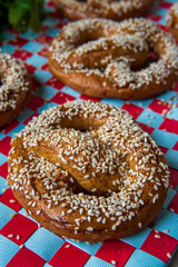 Closeup on a freshly baked homemade soft pretzel with sesame seeds and garlic flakes, ready to eat and hot from the oven. Tasty gluten free savory pastry with a knot on a vibrant, colorful, background
