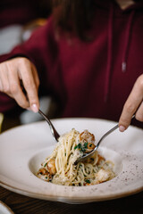 Person eating pasta with shrimps.