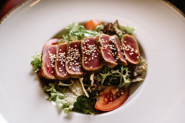 Tuna salad with tomatoes, decorated with sesame seeds.