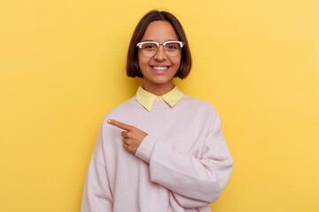 Young student mixed race woman isolated on yellow background smiling and pointing aside, showing something at blank space.