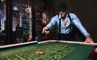 brutal athletic man dressed in suit with a cigar plays in a casino                         
