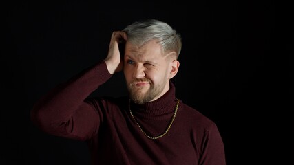 Frustrated confused young man scratching head contemplating how to solve problem, thinking intensely with puzzled look, having doubts on black background. Fashion people uncertain clueless expression