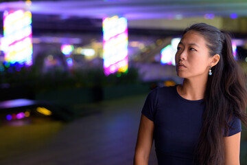 Portrait of beautiful Asian woman thinking outdoors at night