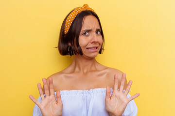 Young mixed race woman isolated on yellow background rejecting someone showing a gesture of disgust.