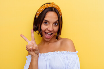 Young mixed race woman isolated on yellow background joyful and carefree showing a peace symbol with fingers.