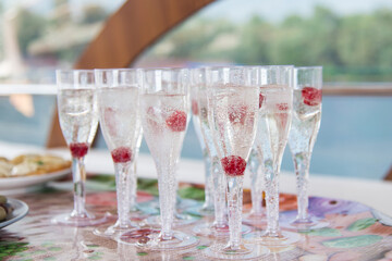 Delicious sparkling white champagne with fresh raspberries served in stylish glasses for a romantic celebration or special occasion