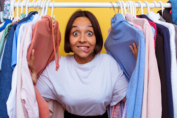 Young girl coming out of a coat rack isolated on yellow background