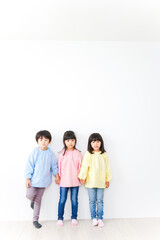 壁に並ぶ3人の幼稚園児