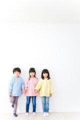 壁に並ぶ3人の幼稚園児