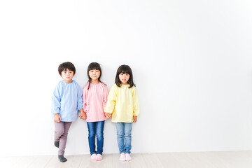 Obraz premium 壁に並ぶ3人の幼稚園児