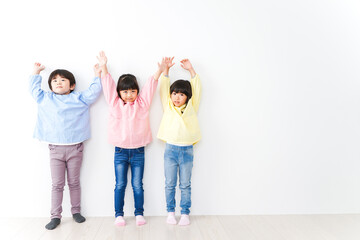 Fototapeta premium 壁に並ぶ3人の幼稚園児
