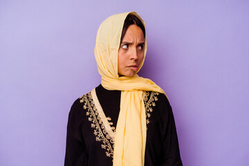 Young arab woman wearing a typical Arabian costume isolated on purple background confused, feels doubtful and unsure.
