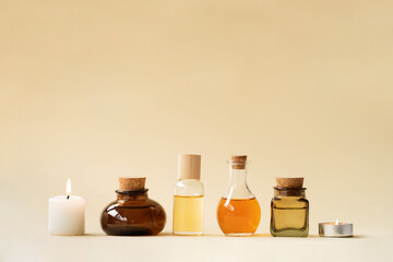 Concise spa composition with oil flasks and candles on beige background.
