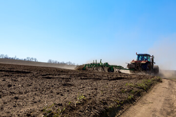 Fototapeta premium Tractor with Plow Tilling a Agricultural Field