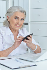 Elderly woman using smartphone in office